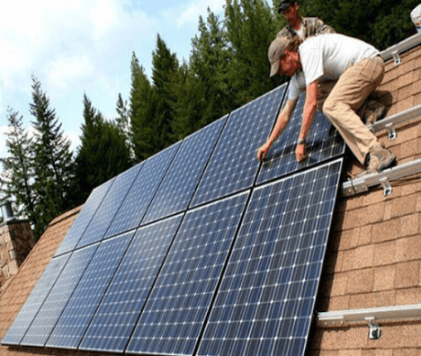 Two solar power installers working on house