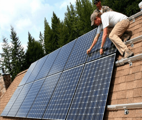 Two solar energy installers working on house